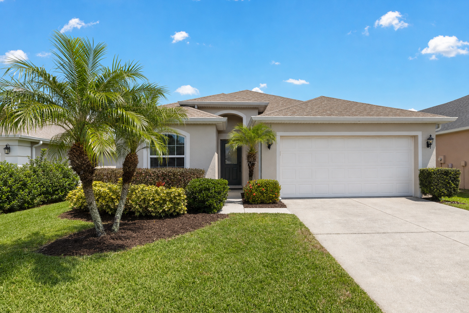 Modest single-family home front yard with palms and tidy shrubs landscaped by Blue Stream in Lakewood Ranch